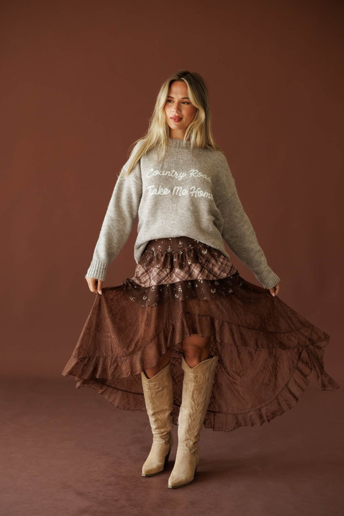Country Roads Sweater in taupe, full-length view on model with a ruffled brown skirt