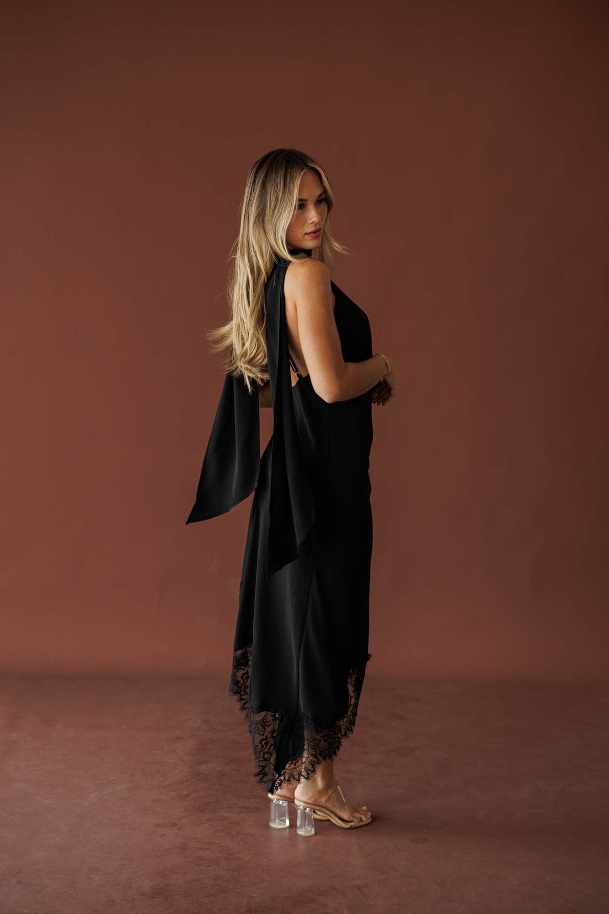 Side back view of the black midi dress showing the open back and long scarf ties