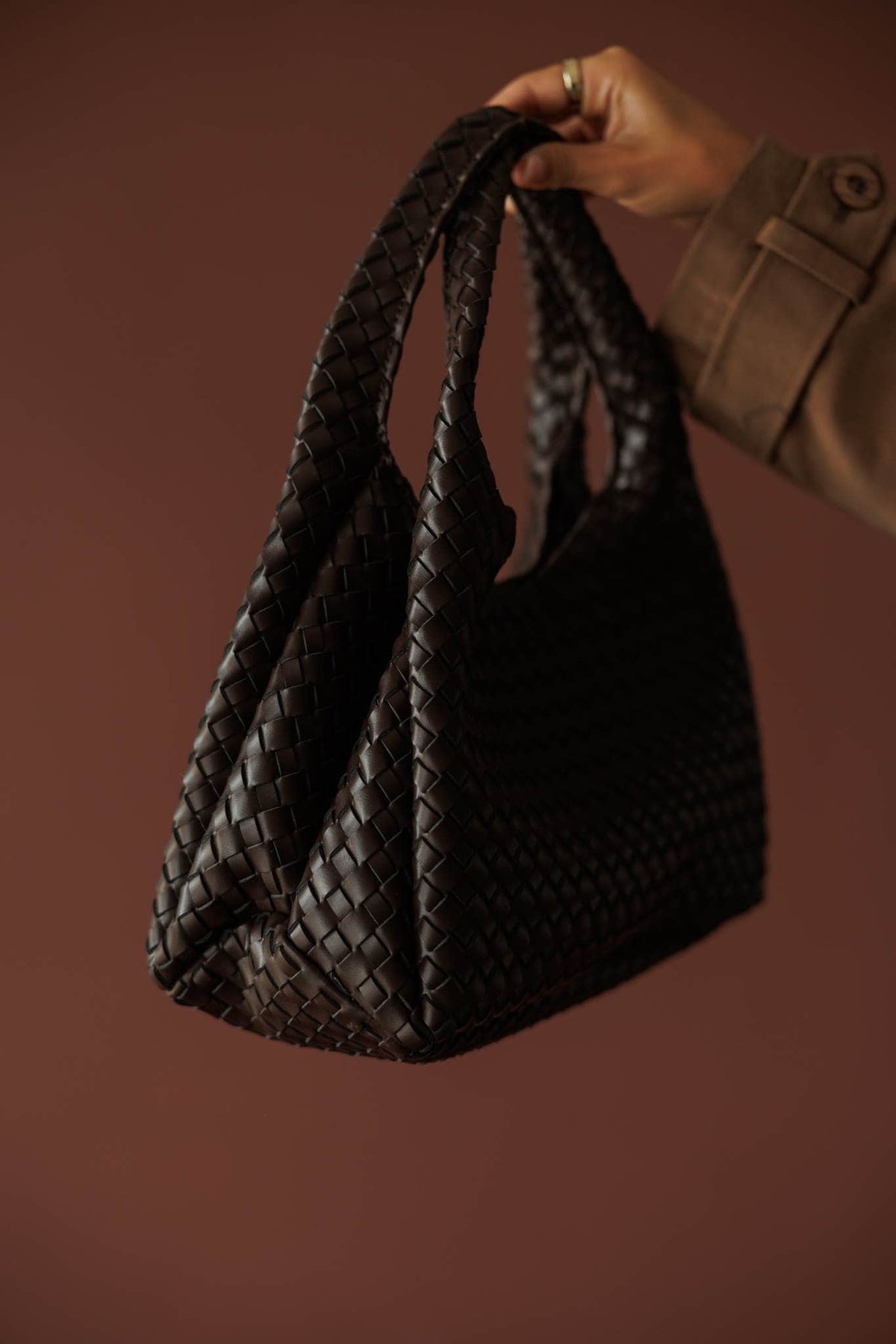 Novie Shoulder Bag***, in chocolate, three-quarter view of the woven bag held by the handles