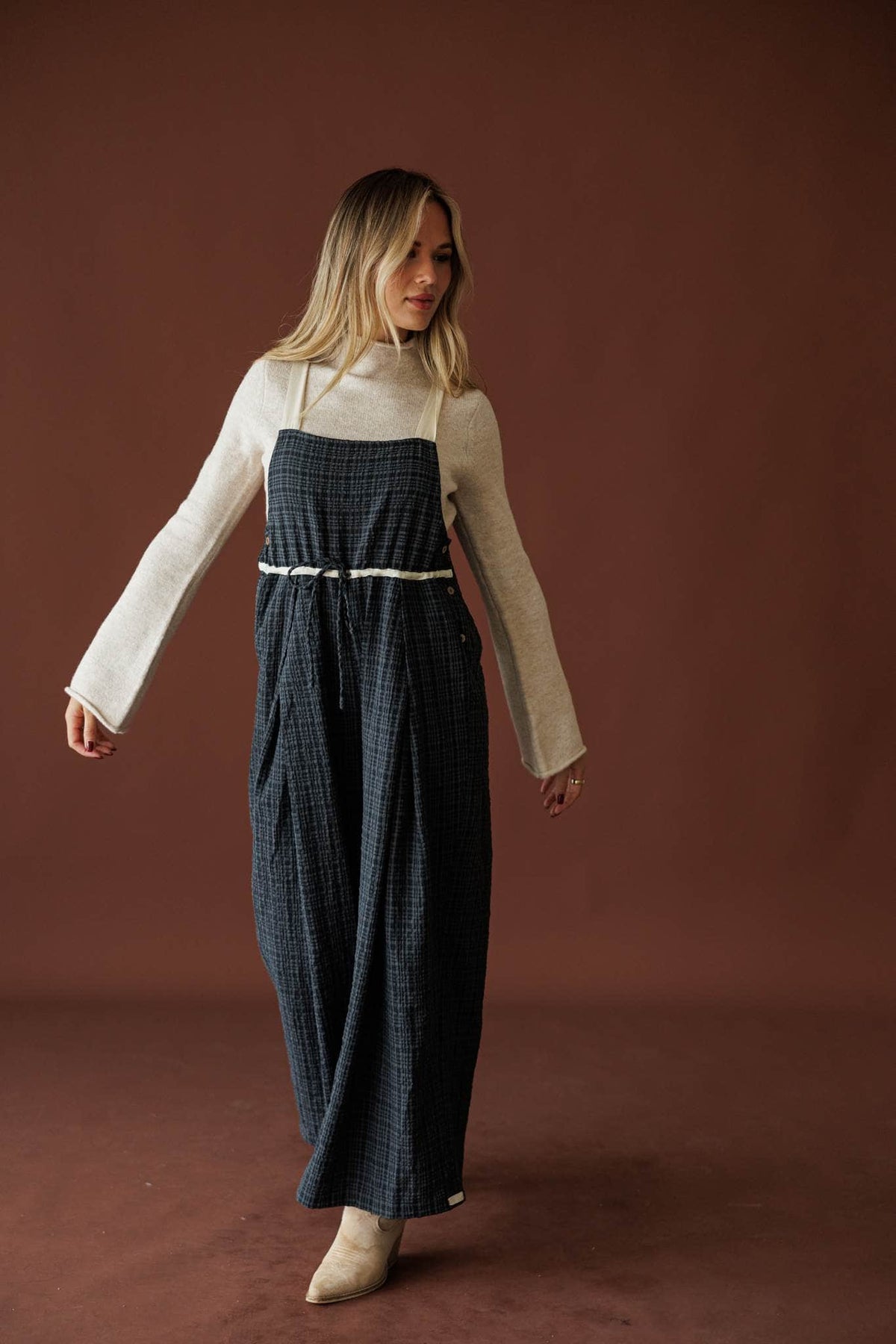 Field Trip Overalls in black plaid, full-length walking view with a cream top