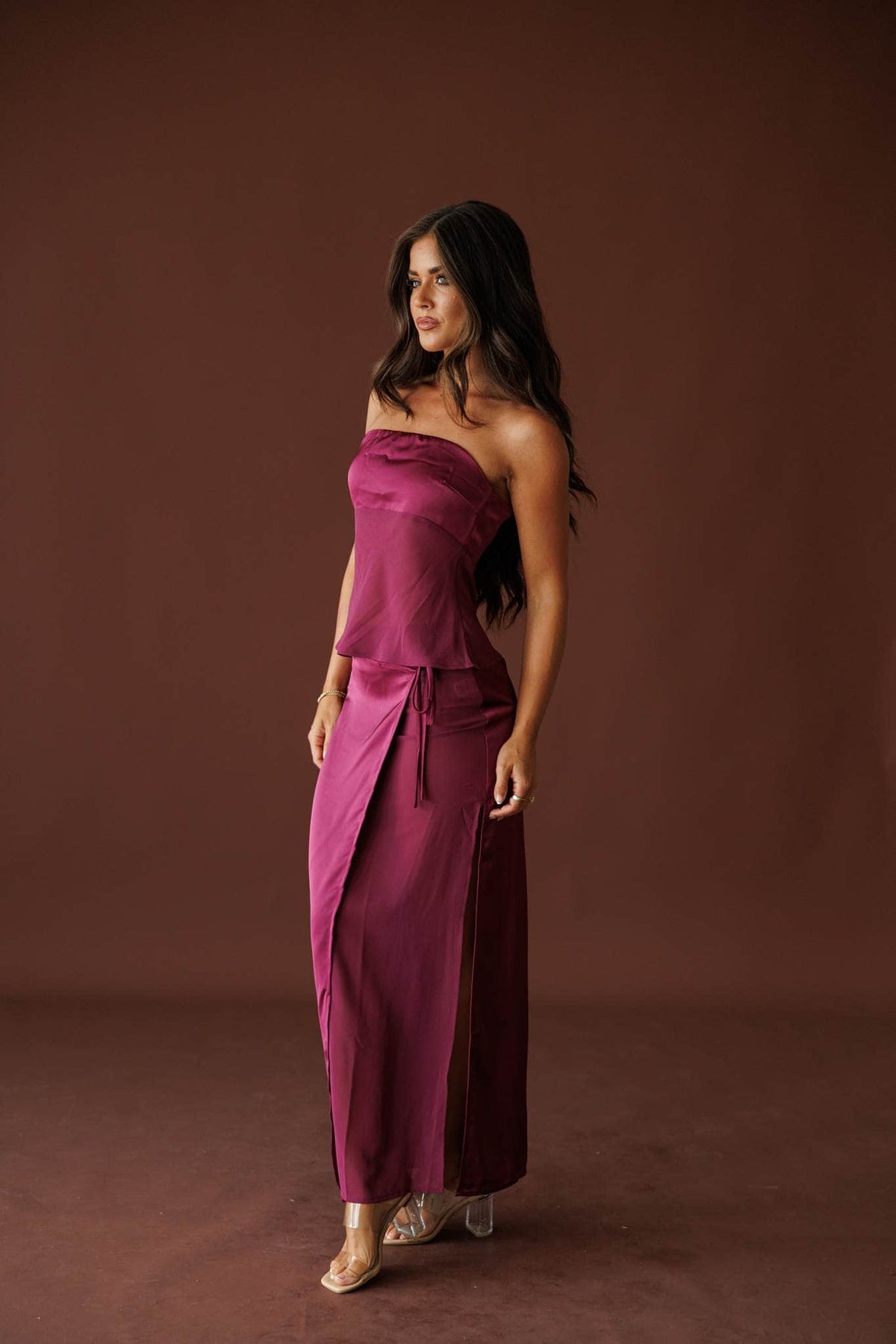 Plum Hour Satin Tube Top in plum, side view on model with a hand at the hip