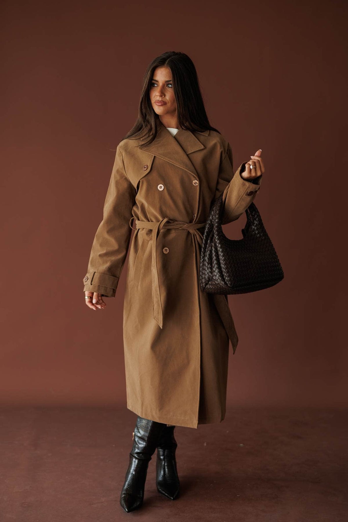 The Estate Walk Trench, in taupe, three-quarter front view with a woven bag