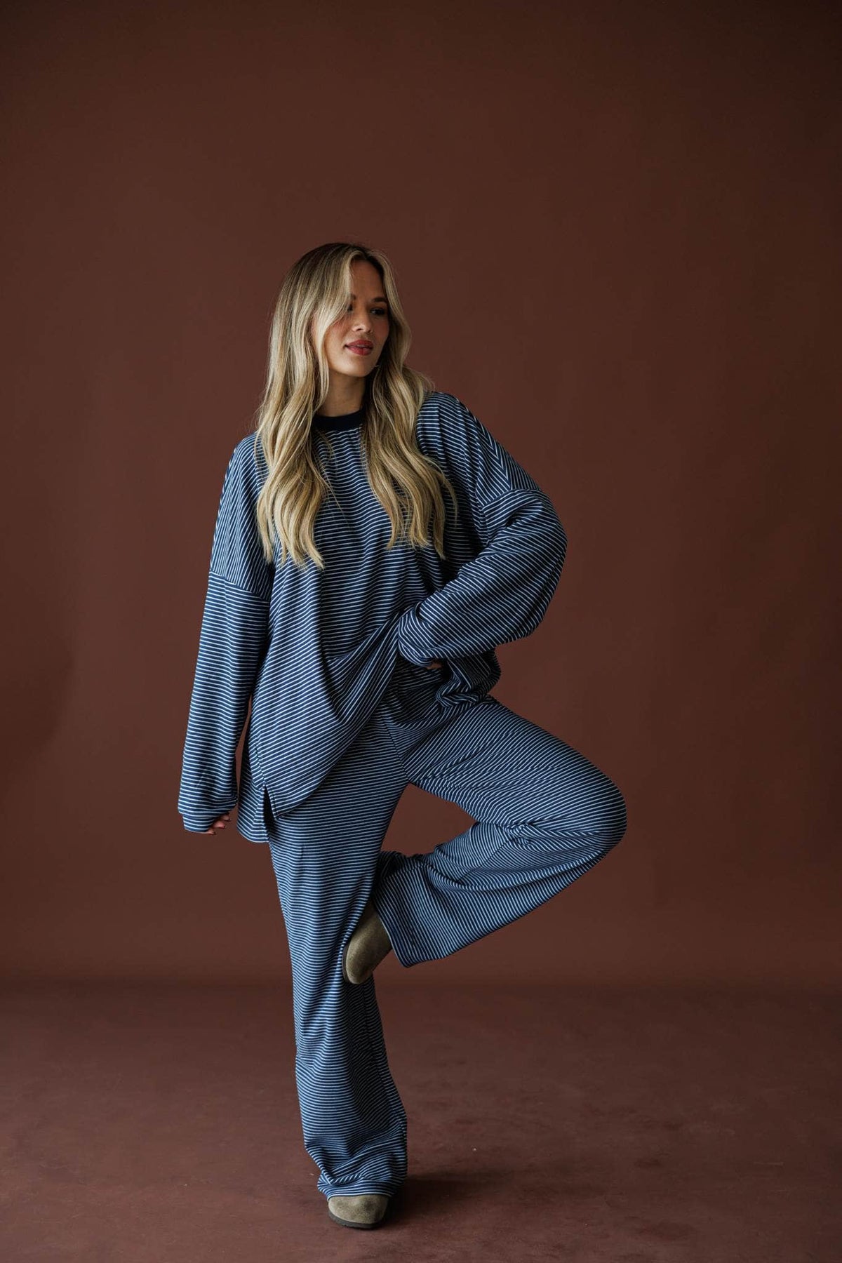 The Social Club Fleece Pants in navy, full-length view on model with one knee raised