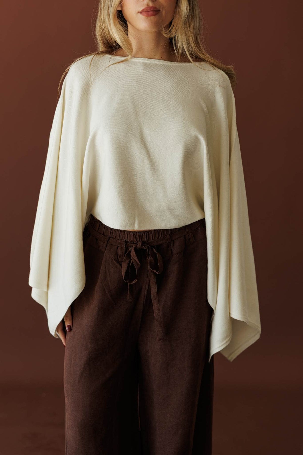 Wide Open Boat Neck Sweater, in cream, front view with brown trousers