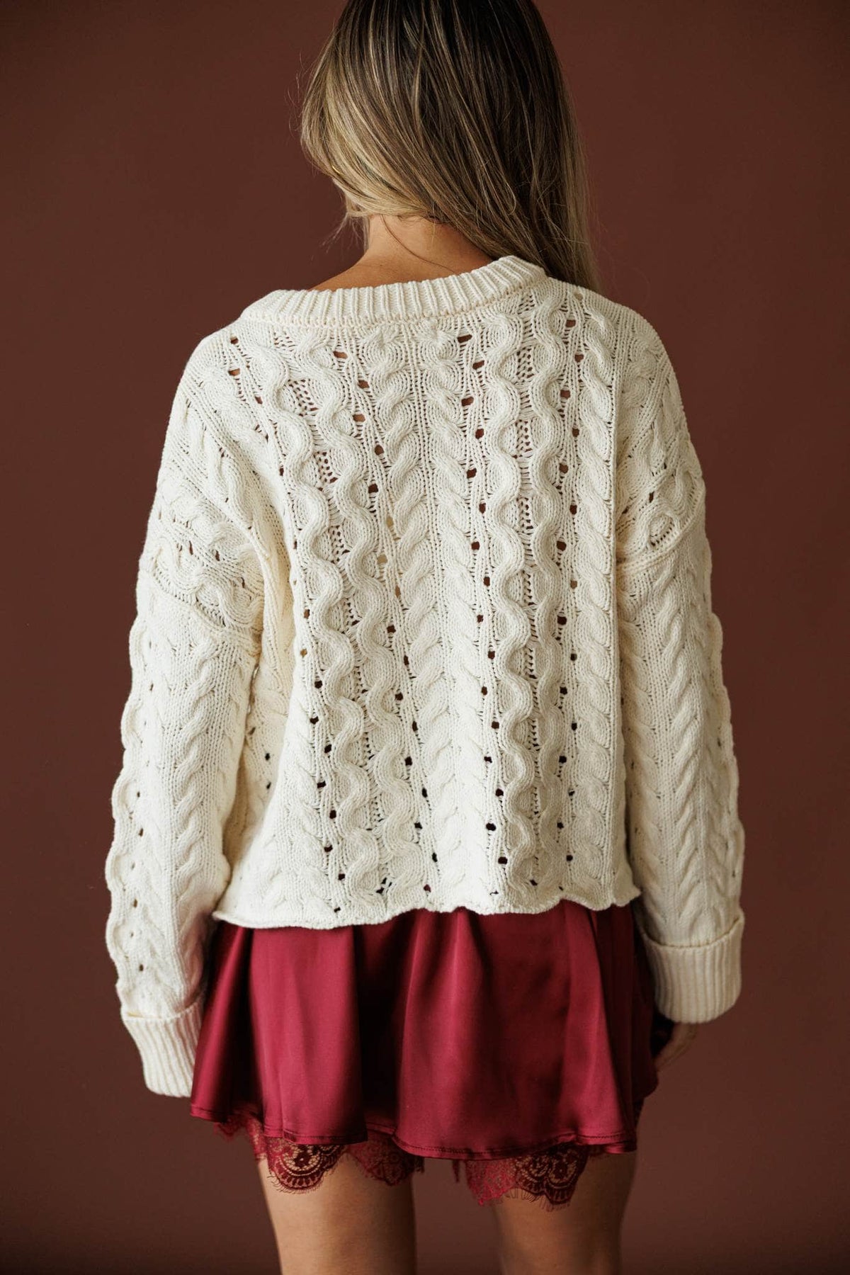 Cable Me Later Sweater in cream, back view showing the curved scooped hem