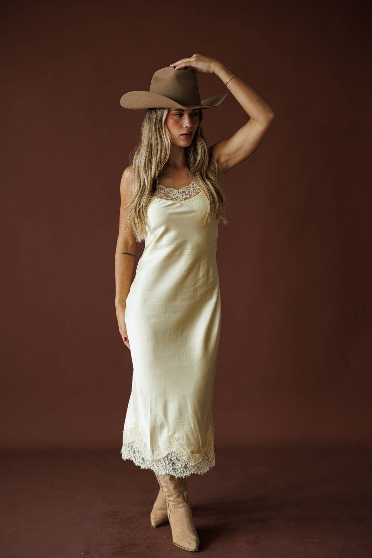 Buttermilk Lace Slip Dress in butter, full-length view on model adjusting a tan hat