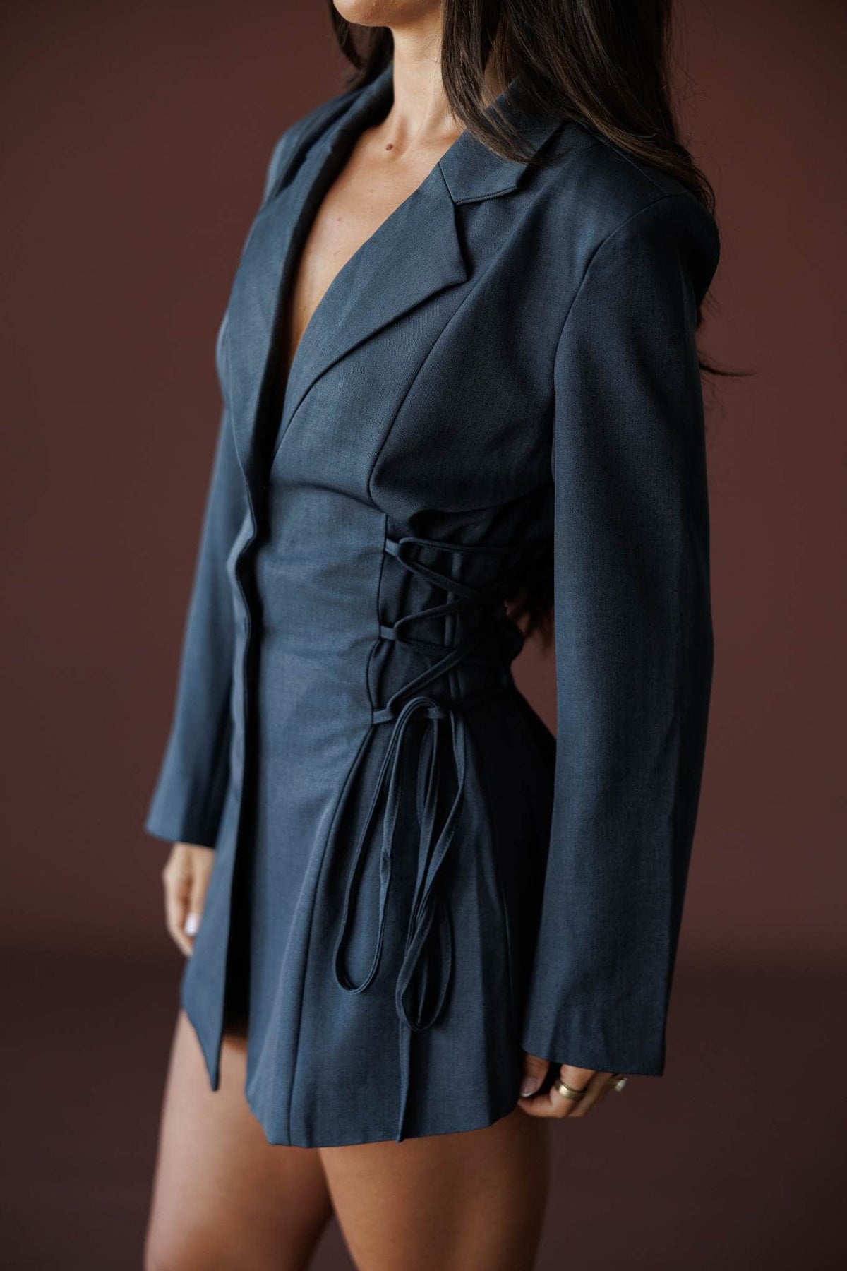 Closing Argument Romper in charcoal, side view showing the lapel and lace up waist