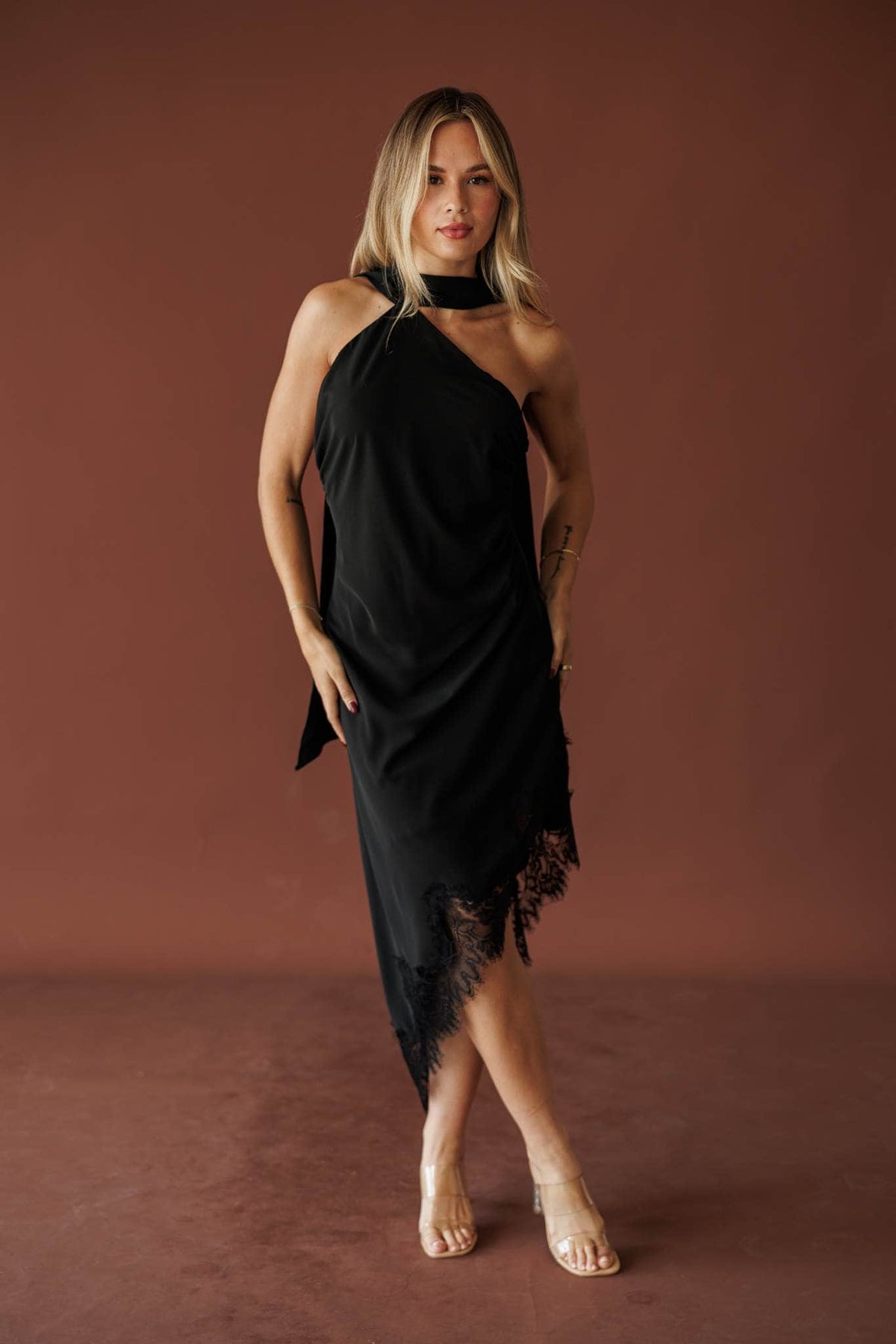 Rylee wearing the black Closing Time one shoulder lace hem midi dress, full-length front view