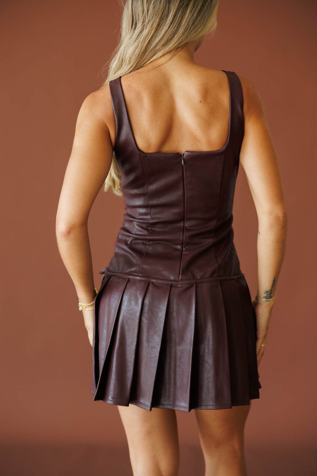 Cover Girl Leather Dress in dark plum, back view showing the leather and pleated skirt