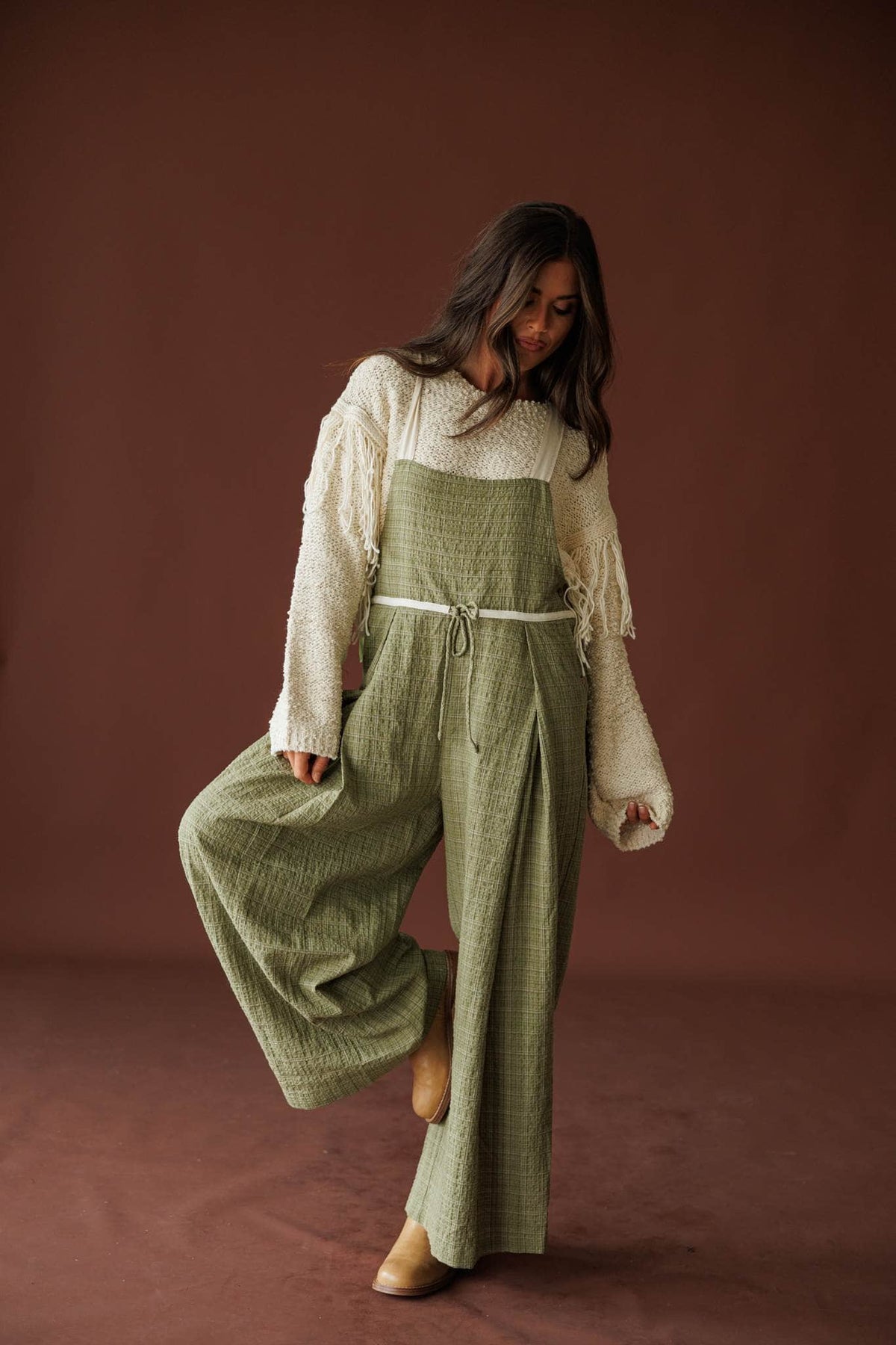 Field Trip Overalls in olive, full-length walking view over a cream sweater