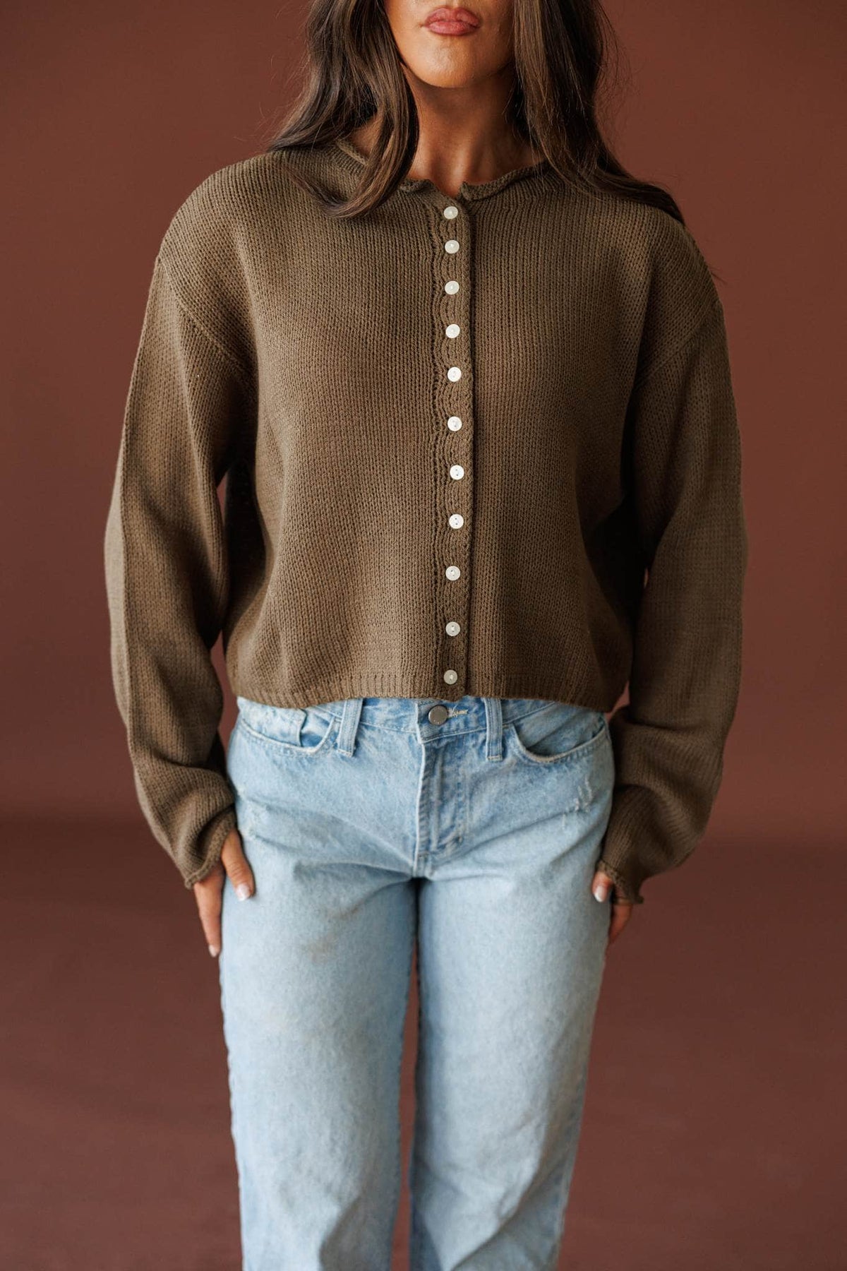Common Ground Cardigan in olive, front view on model with hands at the waist