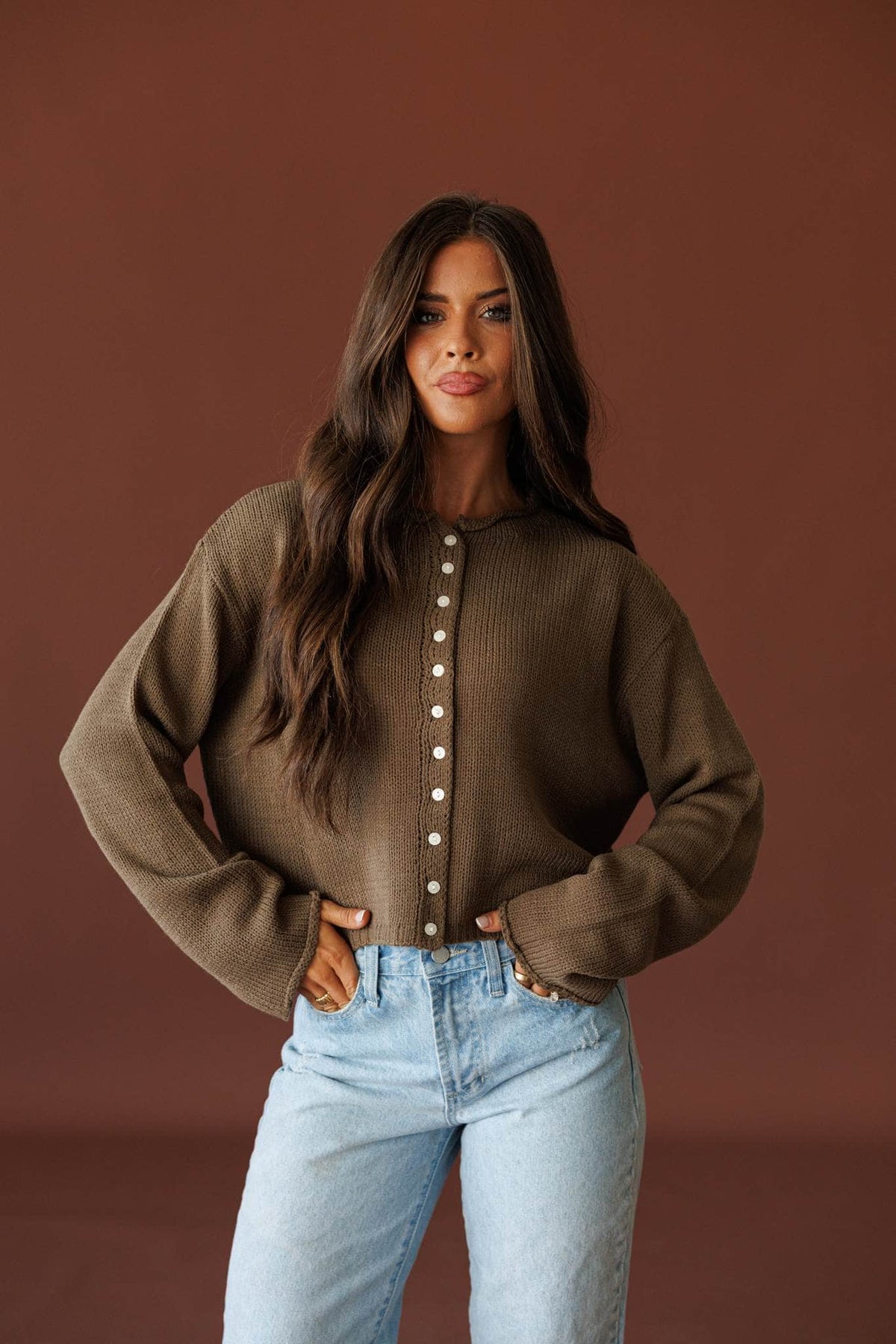 Common Ground Cardigan in olive, full-length view with light wash jeans and hands in pockets