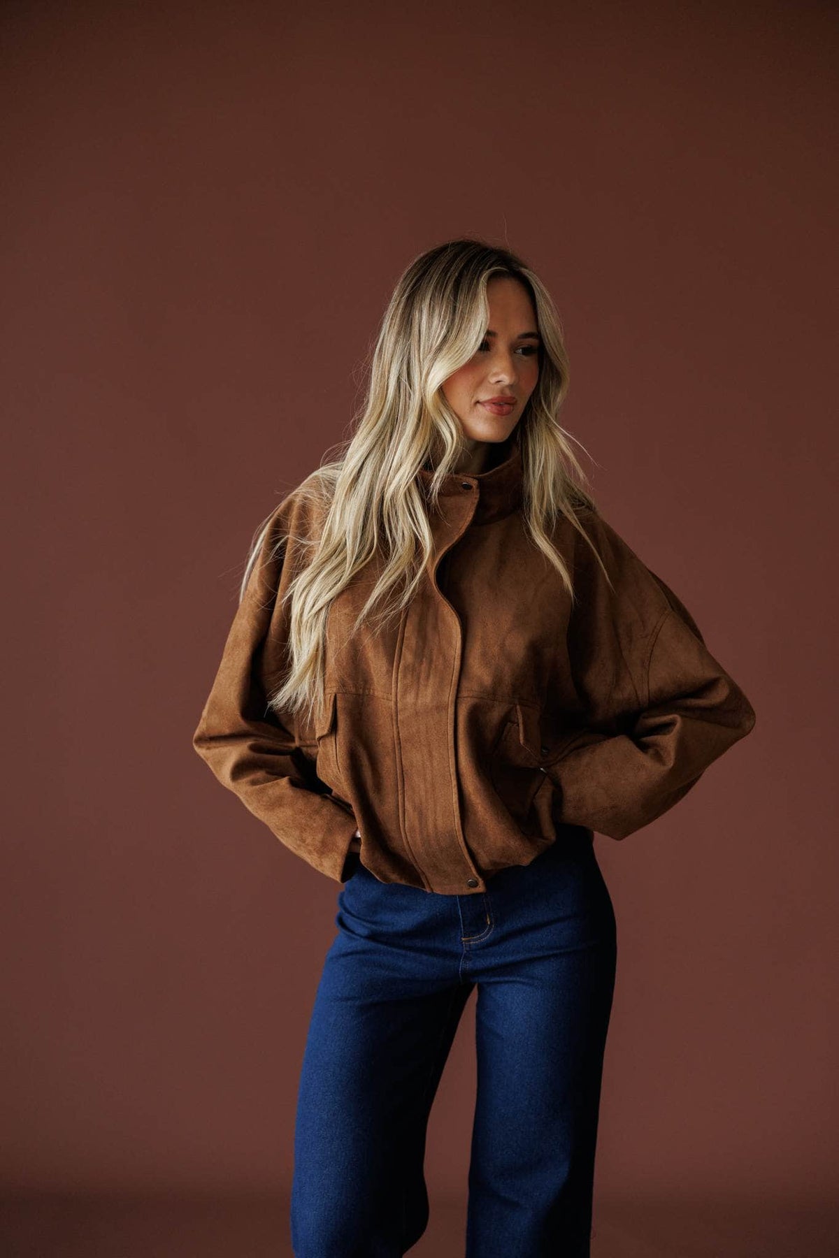 The Outsider Jacket in brown, front view on model with hands at the waist