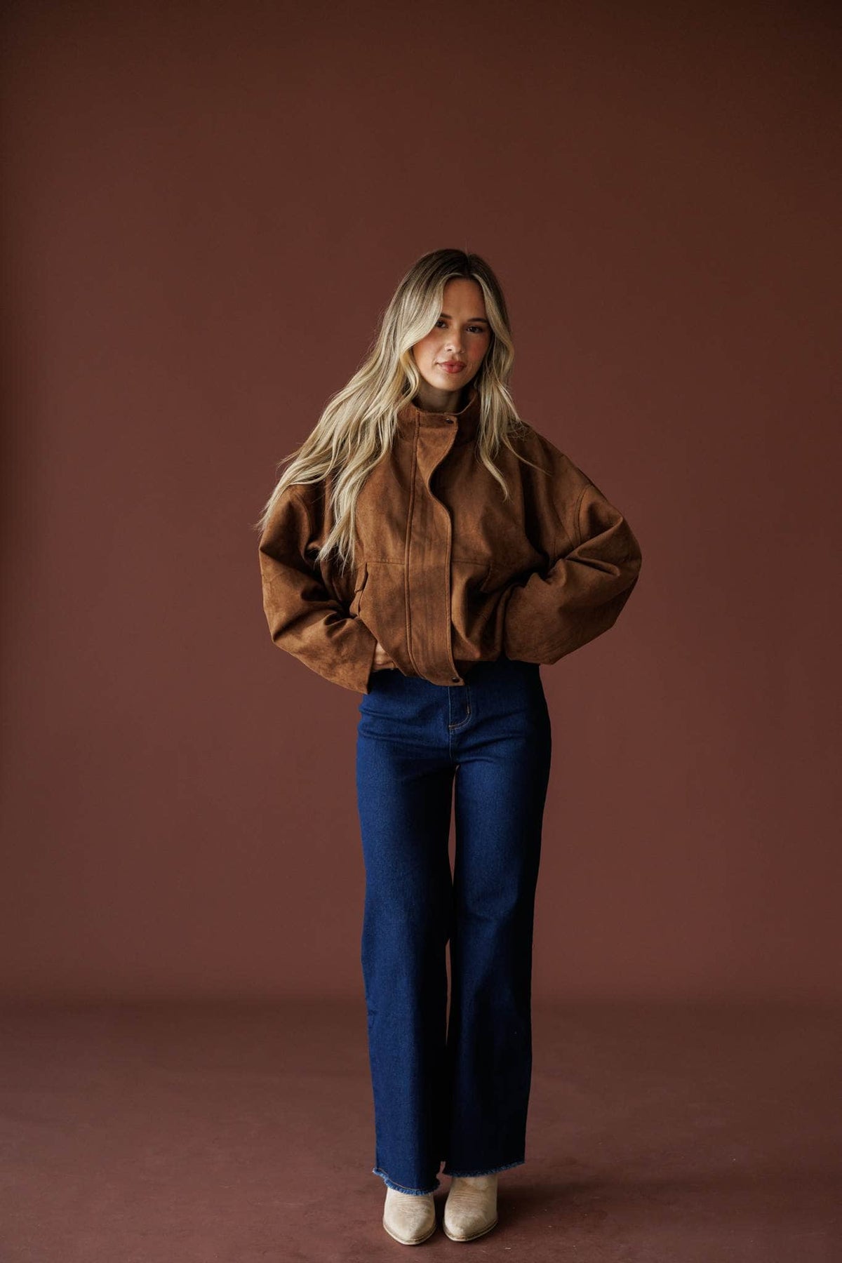 The Outsider Jacket in brown, full-length view on model with hands on hips
