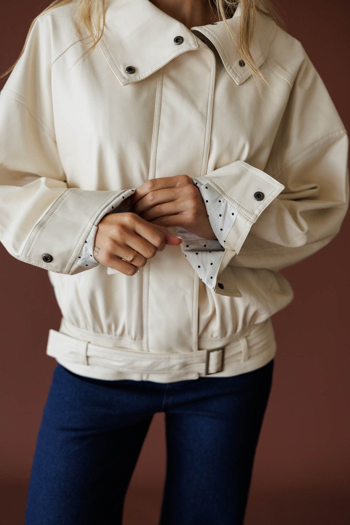 The Waypoint Jacket in cream, front close-up of the snap collar and belted hem