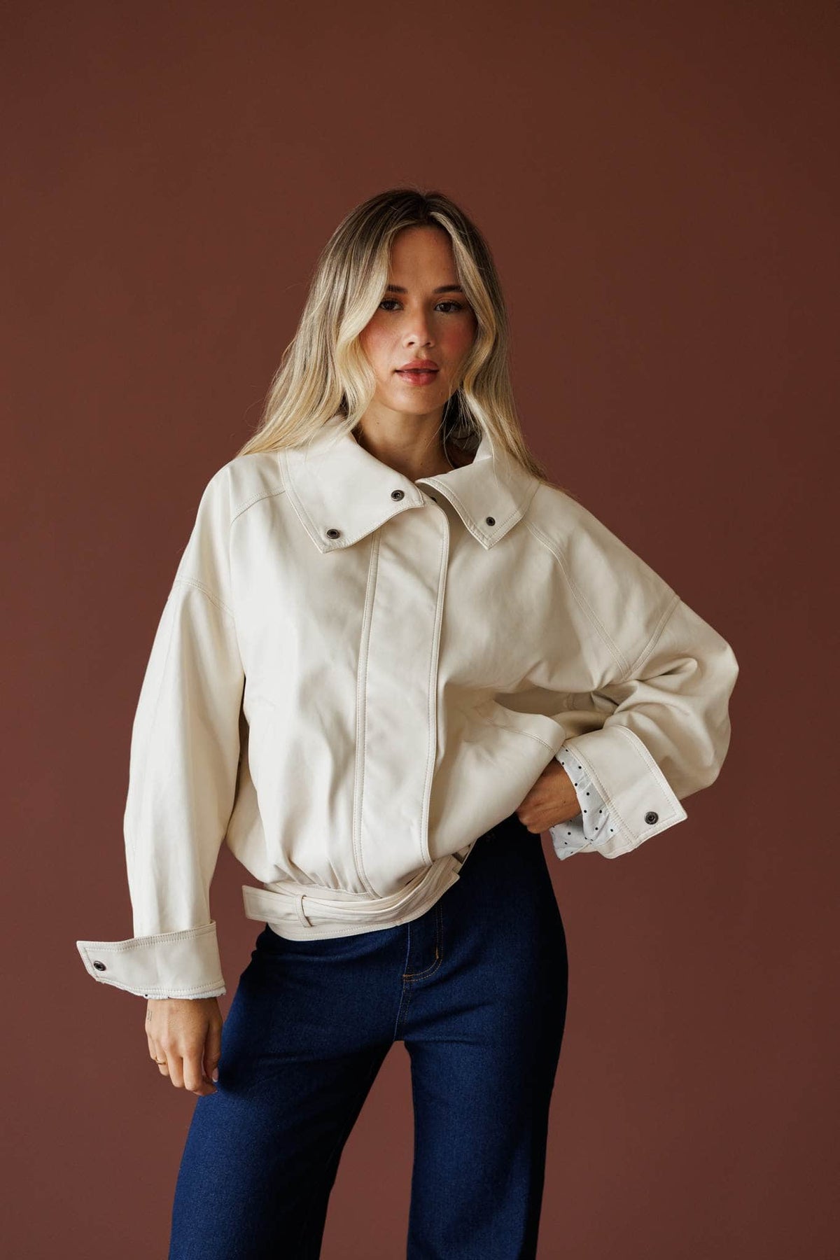 The Waypoint Jacket in cream, front view on model with hand at the waist