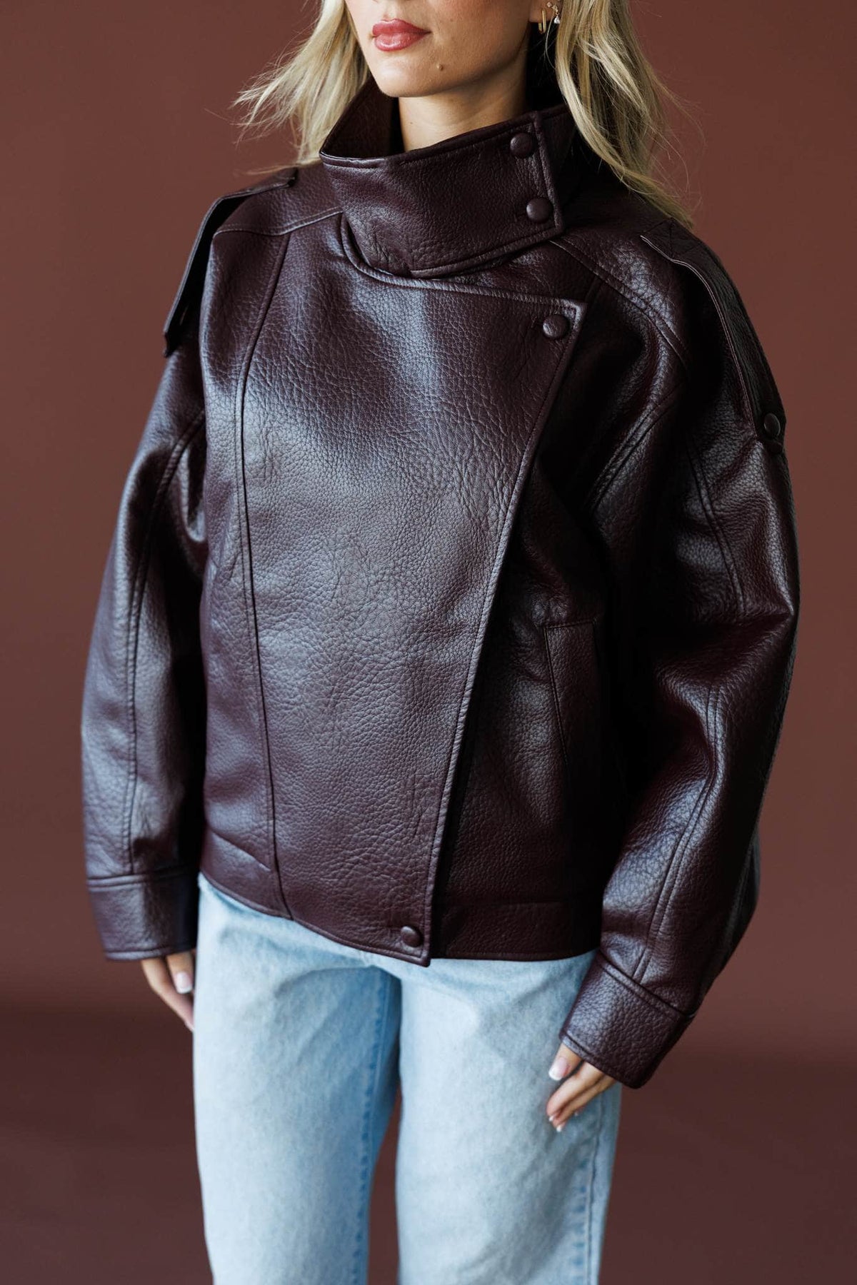 Unlisted Leather Jacket in burgundy, front close-up of the asymmetric zip and collar