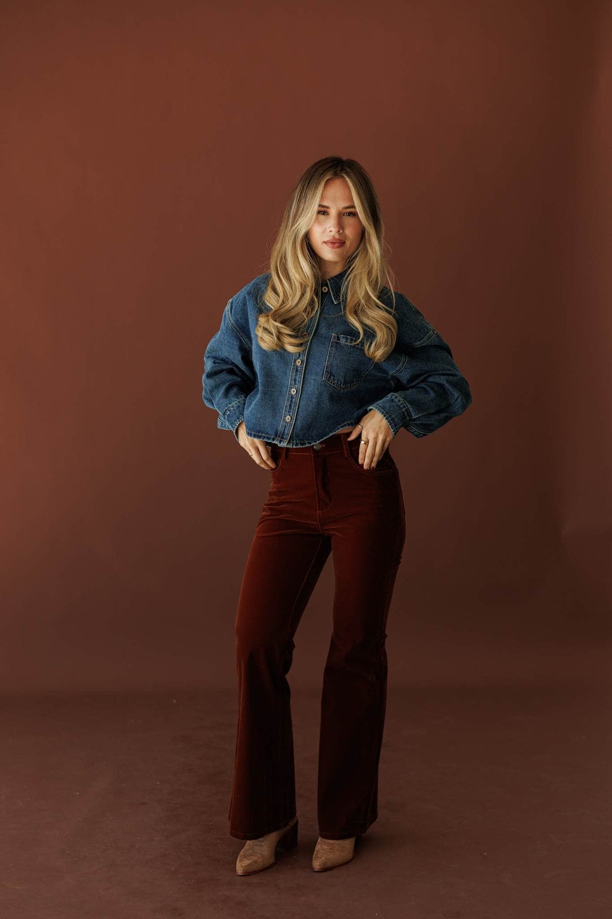 After Dark Velvet Flare Pants, in mulberry, full-length view with a denim jacket