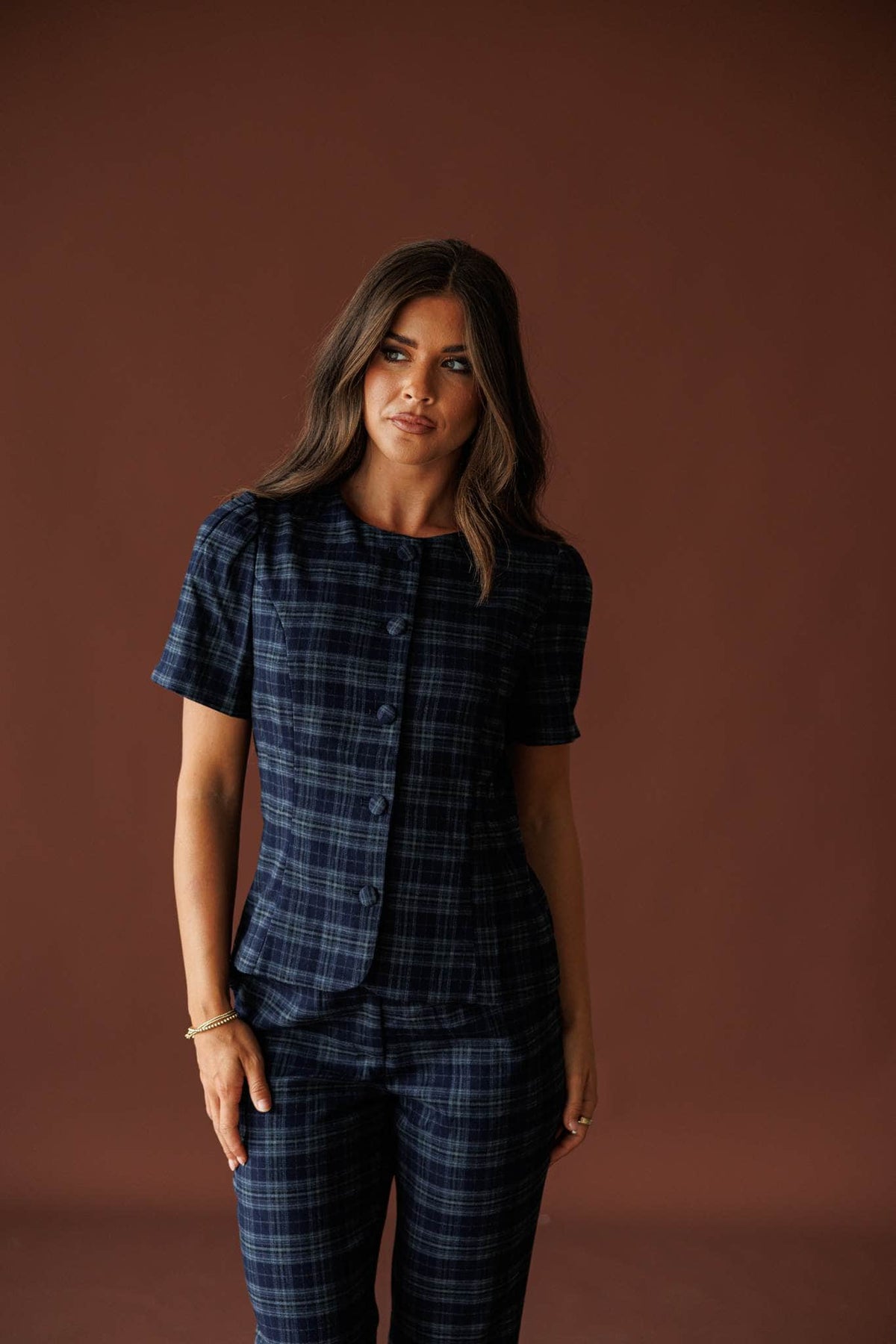The Socialite Top in teal plaid, front view with hands in the pockets of the matching pants