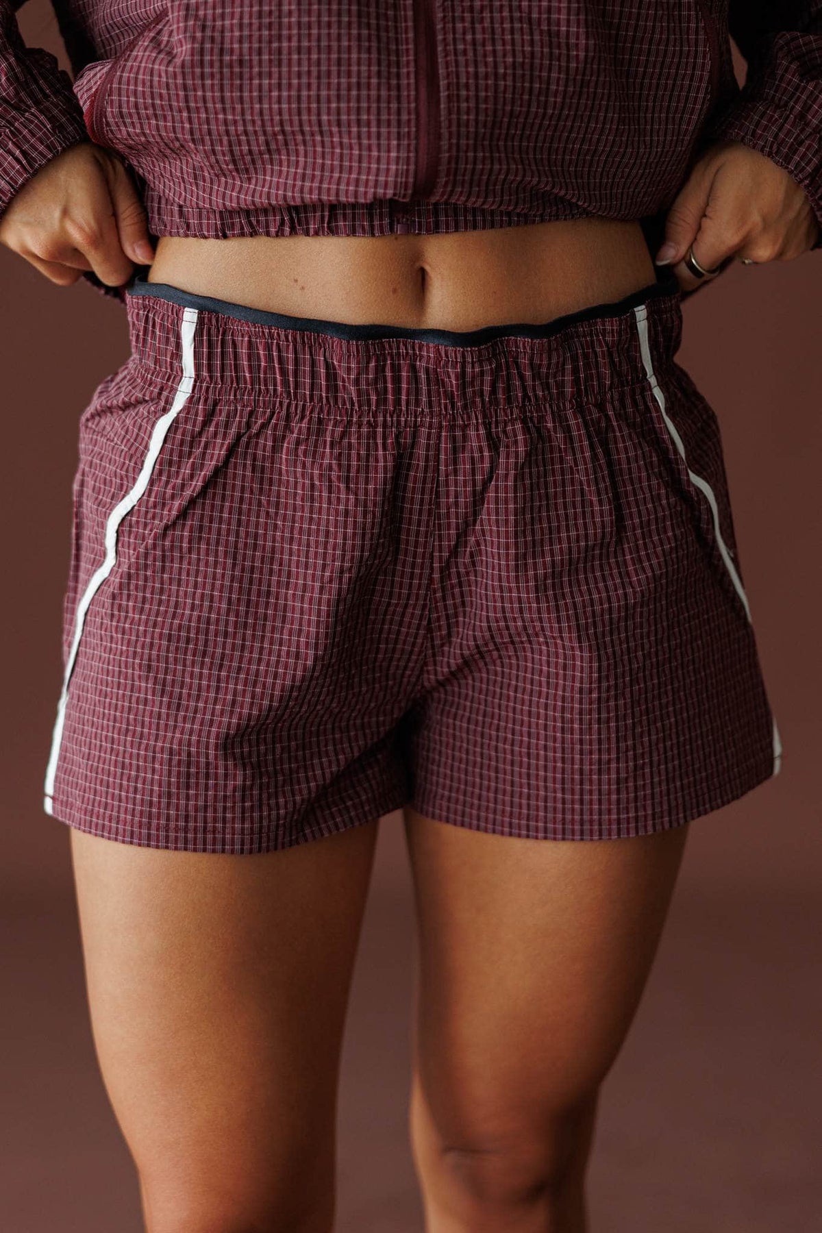 Off Duty Track Shorts in burgundy, front close-up of the elastic waist and side piping
