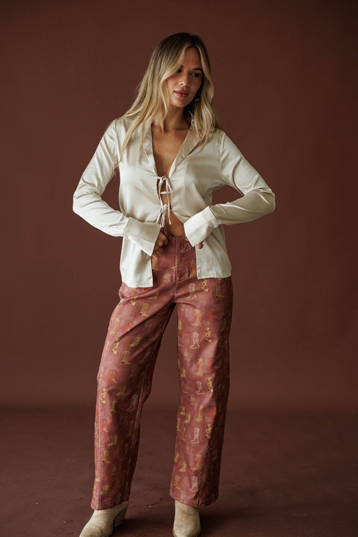 Rodeo Road Printed Pants in brick red, full-length view with a cream cardigan