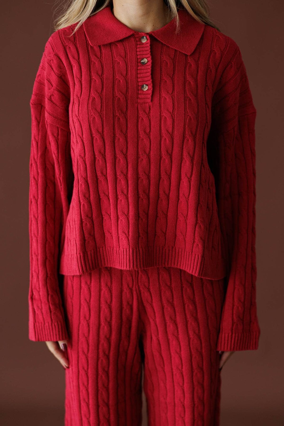Cherry Cable Knit Sweater in red, front view of the collared cable knit on a plain backdrop