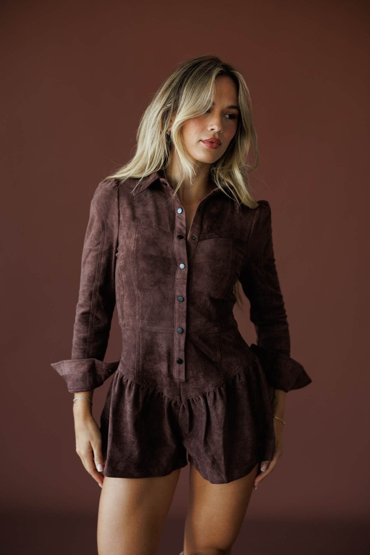 The Outrider Romper in chocolate, front view on model with hands at the sides