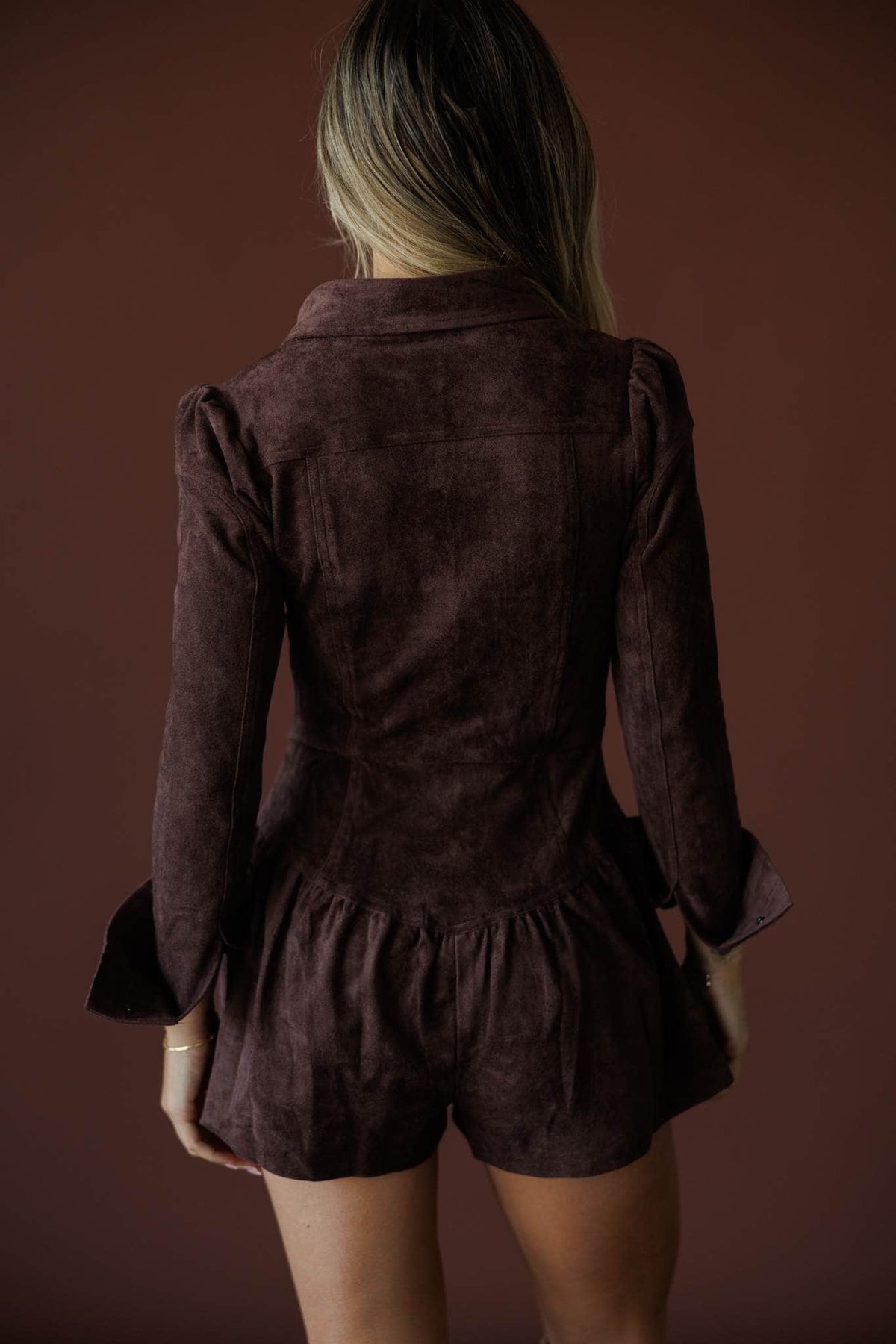The Outrider Romper in chocolate, back view showing the suede romper and ruffle hem