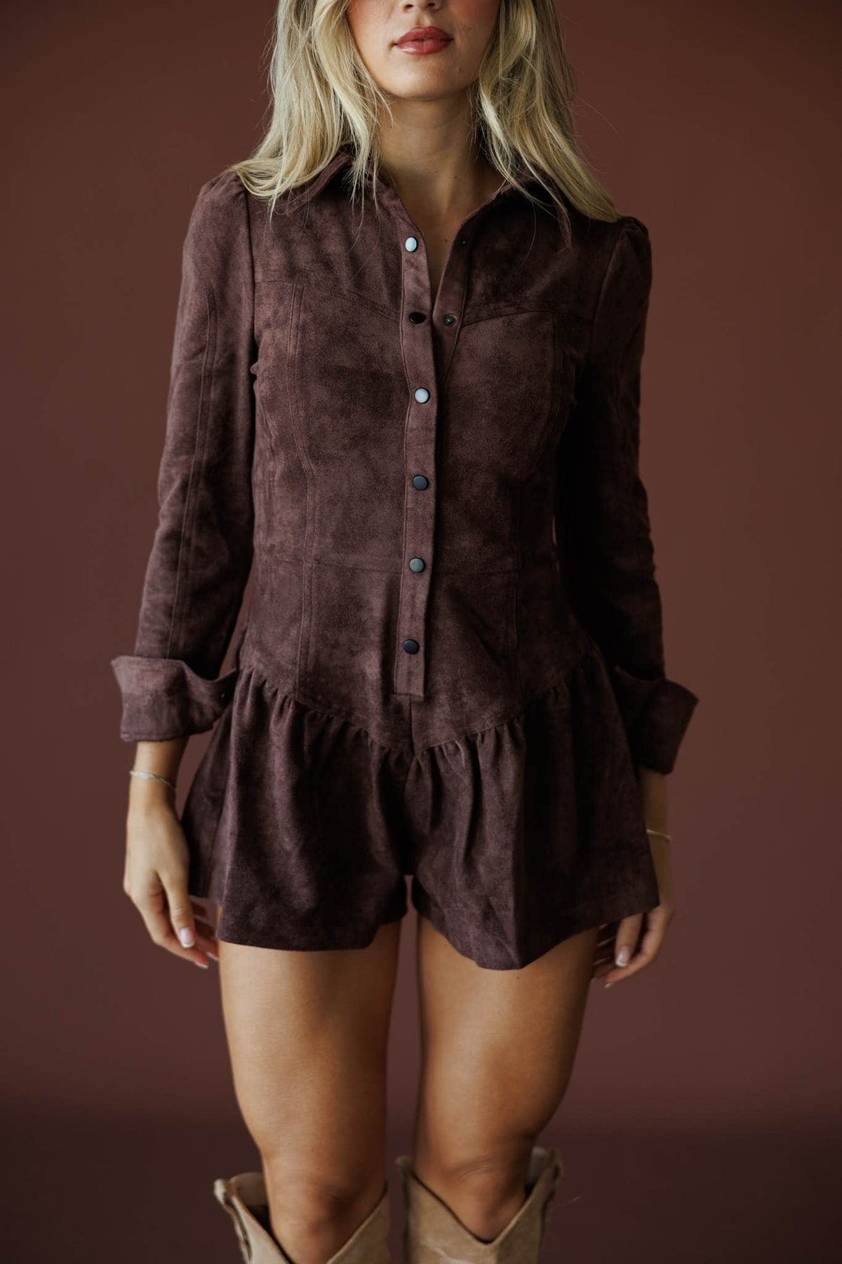The Outrider Romper in chocolate, front close-up of the button front and ruffle hem
