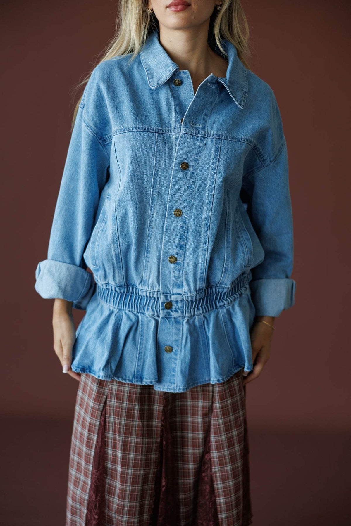 The Remix Denim Jacket in denim blue, front close-up of the button front and peplum