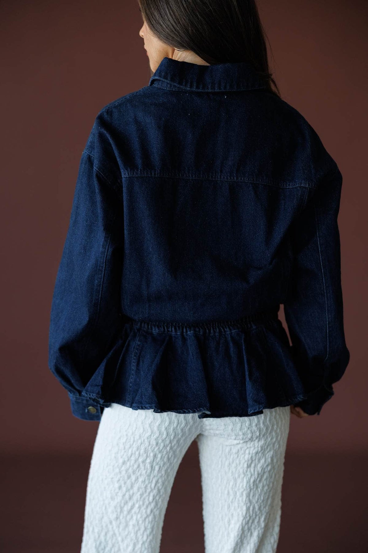 The Remix Denim Jacket in dark denim, back view showing the gathered peplum hem