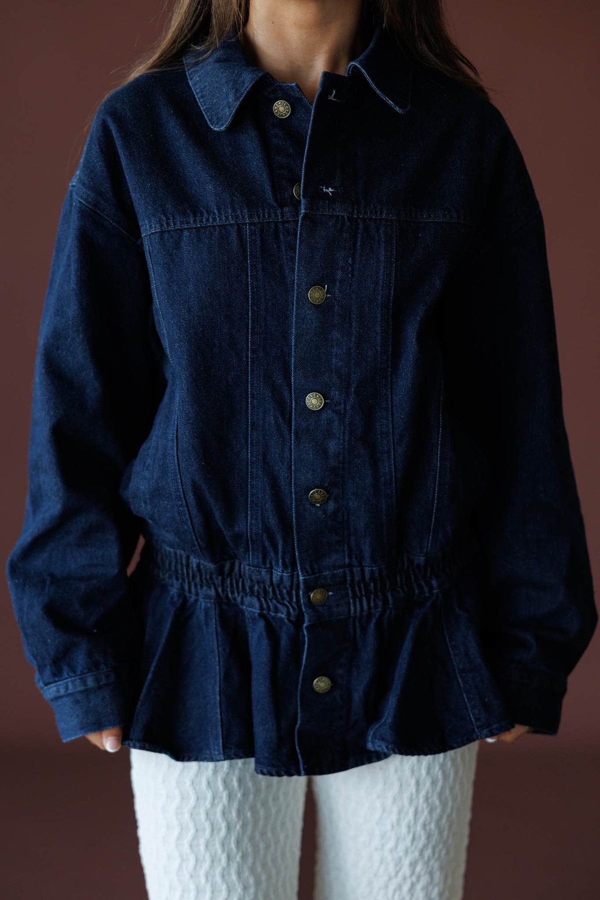 The Remix Denim Jacket in dark denim, front close-up of the button front and peplum