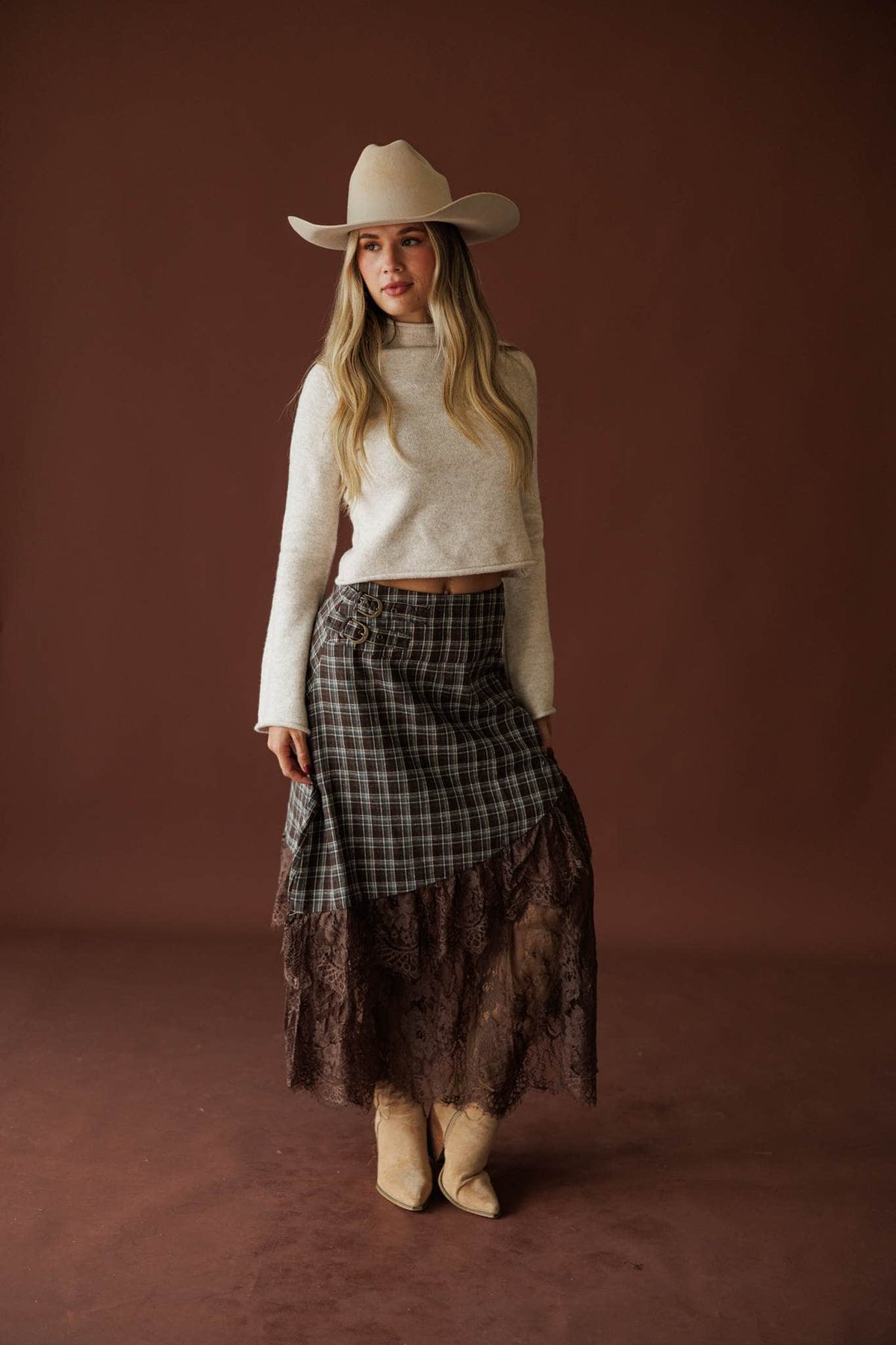 Lost In Wyoming Plaid Skirt in brown, full-length view styled with a cream sweater